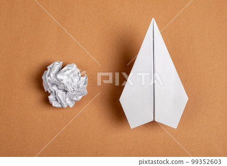 Crumpled paper sheet and origami plane. Creating smth from nothing. Success concept on brown background 99352603