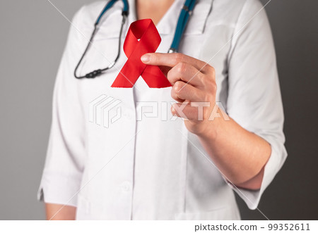 Red satin ribbon in doctors hand, symbol of HIV and AIDS awareness day. 1 December support Red satin ribbon in doctors hand, symbol of HIV and AIDS awareness day. 1 December support 99352611
