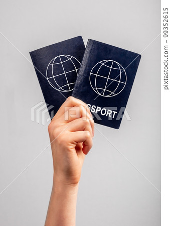 Woman hand with two passports. Family vacation, travel together concept. Identity, nationality verification. 99352615
