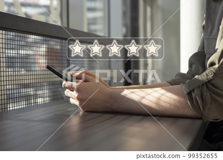 Woman using phone for submitting positive rating. Five star ranking. Evaluation of service, smartphone application or product quality. Client satisfaction 99352655