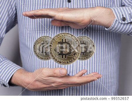 Bitcoin coins levitating between man hands. Cryptocurrency, digital money. Financial concept in abstract style. 99352657