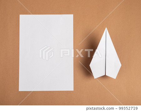 Making origami plane from white paper sheet. Creating, development concept. Blank, material and work result. Assembly procedure on brown background 99352719
