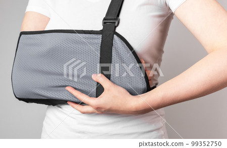 Woman wearing sling to protect painful forearm, wrist. Arm trauma, sprain, injury. Health care concept. Using medical devices for pain reduction Woman wearing sling to protect painful forearm, wrist. Arm trauma, sprain, injury. Health care concept. Using medical devices for pain reduction 99352750