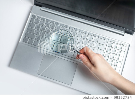 Woman hand holding magnifying glass over laptop keyboard. Information search on Internet concept. Expertise of electronic projects, financial data. 99352784