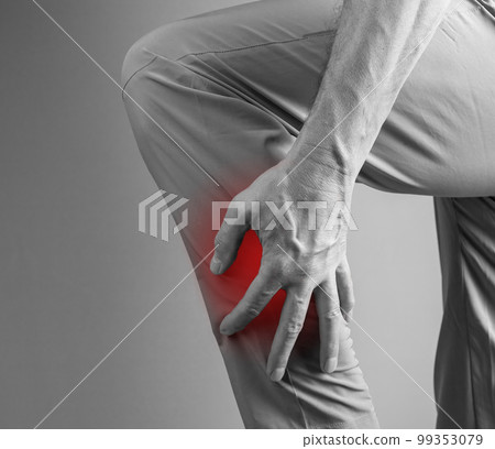 Shin splints. Man holding painful leg with red spot closeup. Overuse injury, cramp, medial tibial stress syndrome. Health care, orthopedic problems and treatment concept. Black and white Shin splints. Man holding painful leg with red spot closeup. Overuse injury, cramp, medial tibial stress syndrome. Health care, orthopedic problems and treatment concept. Black and white 99353079