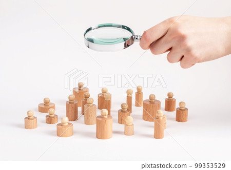 Social research. Hand with magnifying glass over Montessori knobbed cylinders like people community. Sociology concept. 99353529