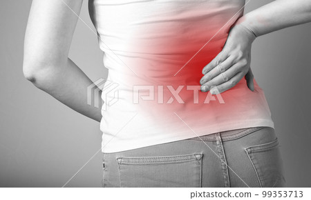 Backache. Woman holding painful lower back with red point closeup. Sport, household injury, chronic diseases. Office syndrome. Health care and medicine concept. 99353713