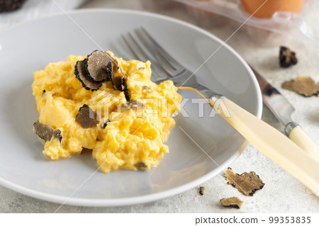 Scrambled eggs with fresh black truffles from Italy served in a plate close up, gourmet breakfast 99353835
