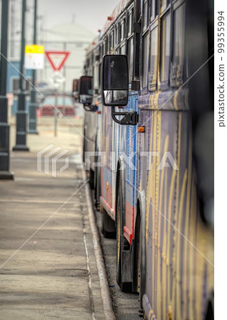 Shallow focus on a mirror of a row of busses with colored graffiti 99355994