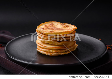Delicious fresh pancakes with berry jam on a black ceramic plate 99356631
