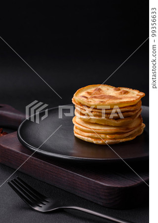 Delicious fresh pancakes with berry jam on a black ceramic plate 99356633