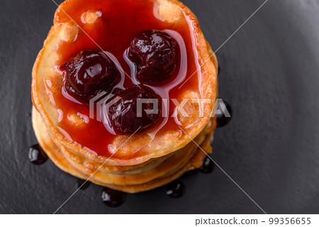 Delicious fresh pancakes with berry jam on a black ceramic plate Delicious fresh pancakes with berry jam on a black ceramic plate 99356655
