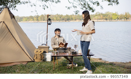 Couple camping for the weekend in the woods near the river, Camping Holiday In Countryside, Camping for the day and recreational activities amidst nature and relaxation, Outdoor leisure activities. Couple camping for the weekend in the woods near the river, Camping Holiday In Countryside, Camping for the day and recreational activities amidst nature and relaxation, Outdoor leisure activities. 99357349