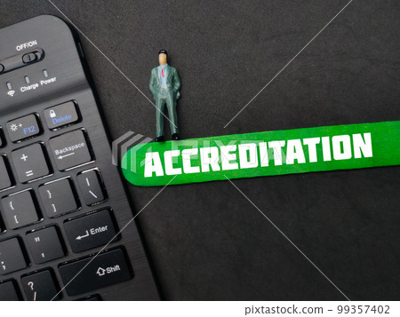 Black keyboard and miniature people with the word ACCREDITATION on black background. 99357402