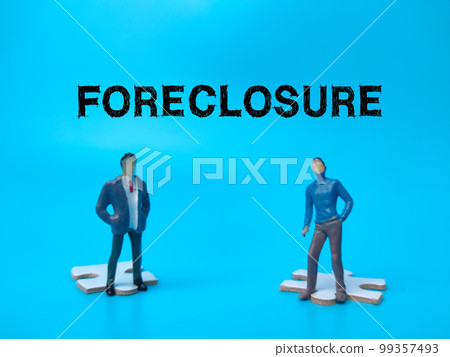 The two miniature people with the word FORECLOSURE on blue background. 99357493