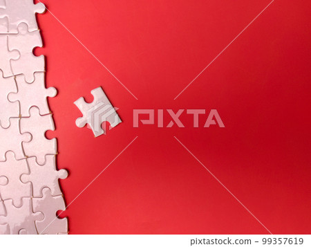 Unfinished white jigsaw puzzle pieces on red background 99357619