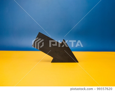 Wooden black arrow with copy space on a yellow and blue background. 99357620