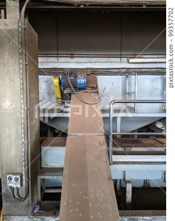 Malaysia, 25 May 2022: A blue palm kernel intake conveyor motor located in a palm kernel processing plant. 99357702