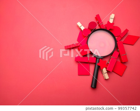 Magnifying glass and colored wooden clips on a red background with copy space. Magnifying glass and colored wooden clips on a red background with copy space. 99357742