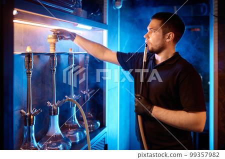 Man engaged in hookah preparation process 99357982