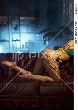 Cropped shot of seductive young woman with sexy booty and legs in yellow harness Cropped shot of seductive young woman with sexy booty and legs in yellow harness 99358014