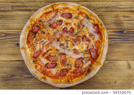 Delicious fresh pizza with sausage, mushrooms and cheese on a wooden table. Top view 99358070