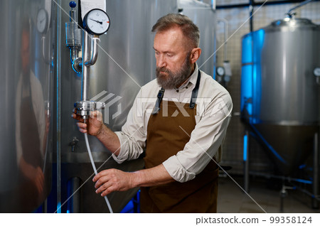 Adult bearded man in workshop of modern industrial brewery 99358124