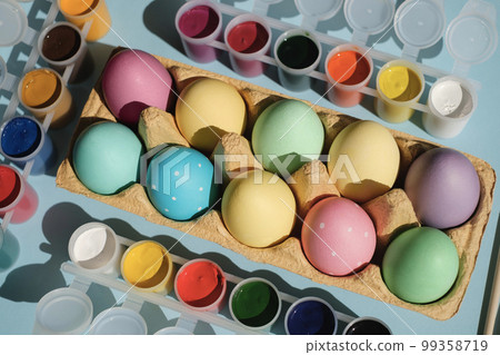 A tray with colored multicolored Easter eggs with a dot. Gouache paint in jars on the table. Preparation for the celebration of Holy Easter A tray with colored multicolored Easter eggs with a dot. Gouache paint in jars on the table. Preparation for the celebration of Holy Easter 99358719