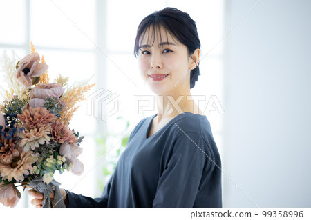 A woman in a gray dress holding a bouquet 99358996
