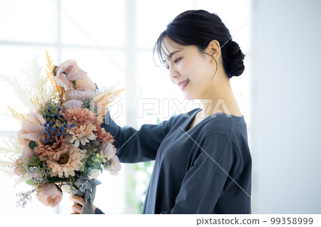 拿著花束的一件灰色禮服的婦女 99358999