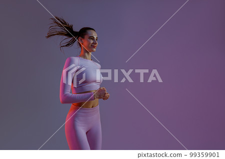 Sporty determined woman running during cardio workout over studio background Sporty determined woman running during cardio workout over studio background 99359901