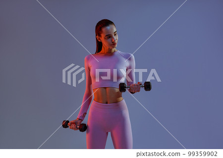 Fitness woman doing exercises with dumbbells on studio background. Strength and motivation 99359902