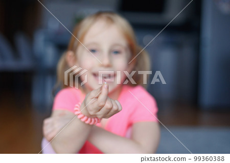 Six year smiling happy girl holding a first fallen tooth and looking at him. 99360388