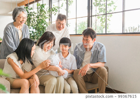 Mom and three generations family holding a baby on the sofa at home 99367615