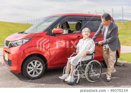 汽車前坐在輪椅上的老年婦女和男子（老人、夫婦、男人和女人） 99370234