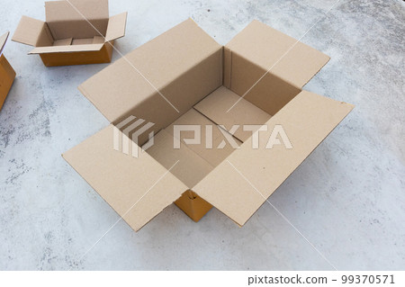 Open empty brown cardboard box on concrete floor Open empty brown cardboard box on concrete floor 99370571