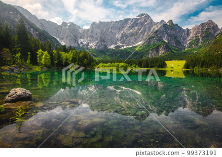 Green forest and clean alpine lake with high mountains, Italy Green forest and clean alpine lake with high mountains, Italy 99373191
