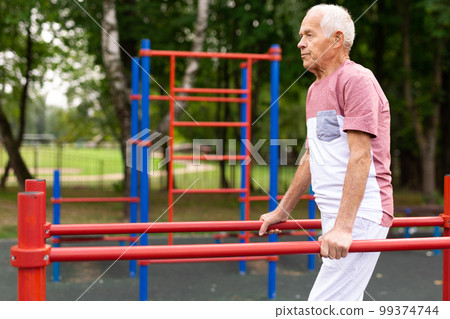 Senior man performing parallel bar exercises in park 99374744