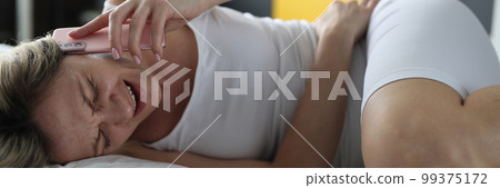 Sick woman is lying in bed and talking on smartphone with doctor Sick woman is lying in bed and talking on smartphone with doctor 99375172