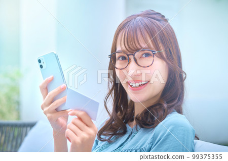 Young woman shopping online with a card Young woman shopping online with a card 99375355