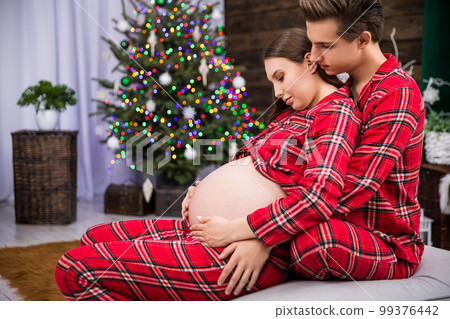 Hugging couple expecting a baby seen in profile 99376442