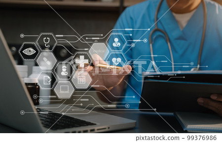 Doctor working with laptop computer and writing on paperwork. 99376986