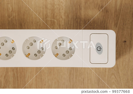 Top view of white cable connector for overloaded power boards at home. Focus at a plug foreground. Macro photo  Top view of white cable connector for overloaded power boards at home. Focus at a plug foreground. Macro photo  99377668