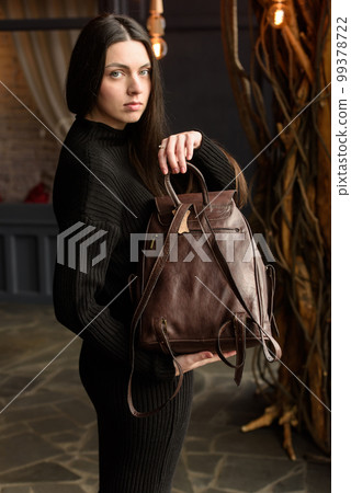 photo of a woman with a brown leather backpack with antique and retro look. indoors photo 99378722
