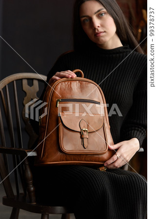 photo of a woman with a brown leather backpack with antique and retro look. indoors photo photo of a woman with a brown leather backpack with antique and retro look. indoors photo 99378737