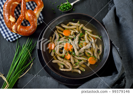 Bavarian, Swabian and Austrian dish - liver spaetzle  in a beef soup served with a crispy pretzel 99379146