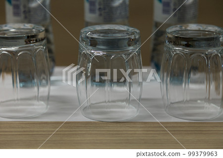 Three inverted empty glasses on a wooden surface. Three inverted empty glasses on a wooden surface. 99379963