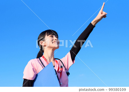A female nurse wearing a scrub standing against the blue sky, a medical worker, a doctor, an outpatient, a medical examination, trimming up A female nurse wearing a scrub standing against the blue sky, a medical worker, a doctor, an outpatient, a medical examination, trimming up 99380109