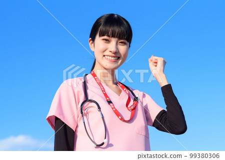 A female nurse wearing a scrub standing against the blue sky Medical worker Doctor Guts pose Trimming up A female nurse wearing a scrub standing against the blue sky Medical worker Doctor Guts pose Trimming up 99380306