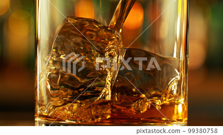 Detail of pouring whiskey into glass with ice cubes. Detail of pouring whiskey into glass with ice cubes. 99380758